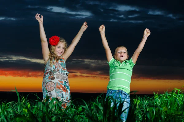 Група щасливих дітей, які грають на лузі, заході сонця, влітку — стокове фото