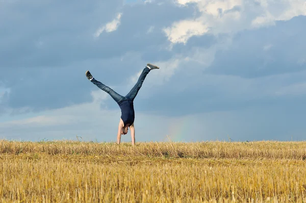 Beautiful girl doing a handstand in a meadow — Stock Photo, Image