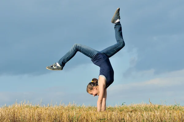 Beautiful girl doing a handstand in a meadow — Stock Photo, Image
