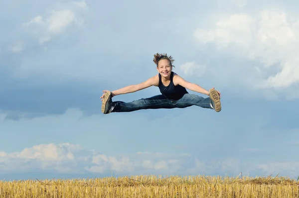 Güzel bir kız olarak mavi gökyüzü karşı jimnastik atlama — Stok fotoğraf