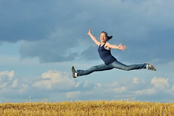 Güzel bir kız olarak mavi gökyüzü karşı jimnastik atlama — Stok fotoğraf