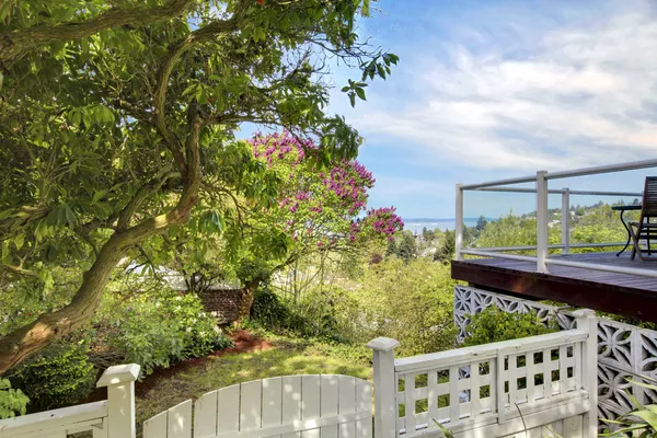 Cour arrière clôture blanche et terrasse avec vue sur l'eau . — Photo