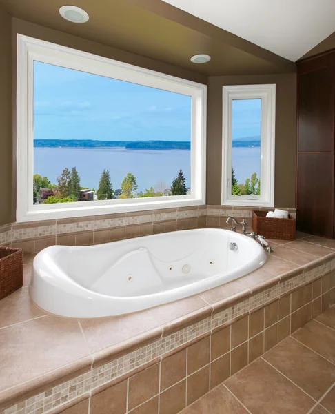 Коричневая ванная комната с новым тюбиком и видом на воду . — стоковое фото