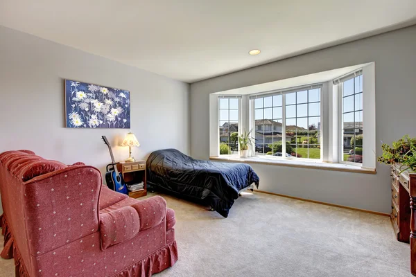 Slaapkamer met groot raam en kleine bed met leunstoel. — Stockfoto