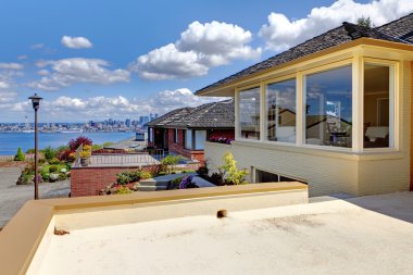 Modern house with patio and view of Seattle and water. clipart