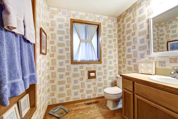 Old brown bathroom with wallpaper and blue towels. — Stock Photo, Image