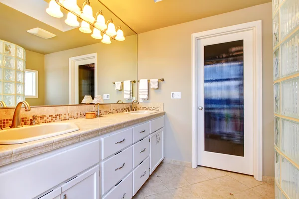 Duża łazienka z białe szafki i przeszkloną kabiną prysznicową. — Zdjęcie stockowe