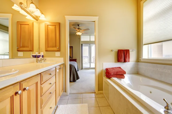 Cuarto de baño con armarios de madera y bañera . — Foto de Stock