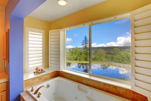 Moderne badkamer met groot ligbad en uitzicht op het meer. — Stockfoto