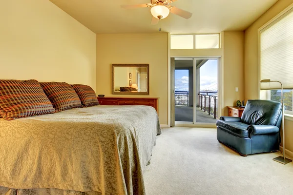 Schlafzimmer mit großem Bett, blauem Stuhl und Balkontür. — Stockfoto