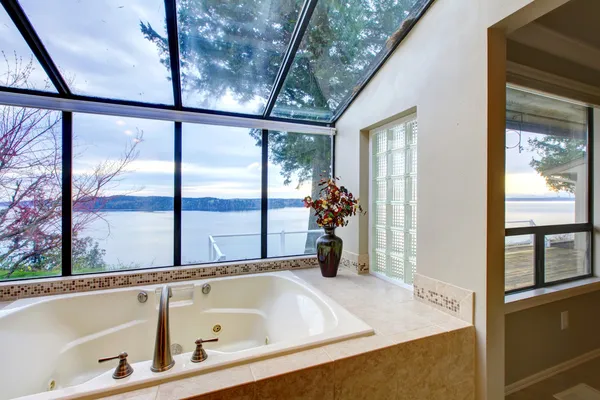 Grote bad met glazen wand met uitzicht op water. — Stockfoto