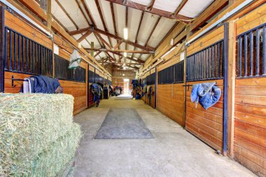 Horse stable interior with hey and wood doors. clipart