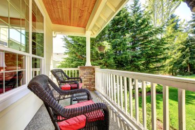 Front porch with brown chairs and red cushions. clipart