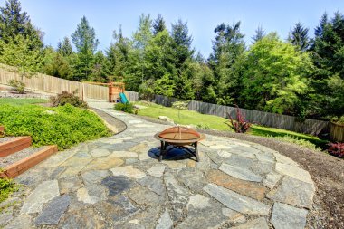 Fenced backyard with stone and fire pit with trees. clipart