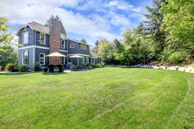 Blue large house with backyard and green landscape. clipart