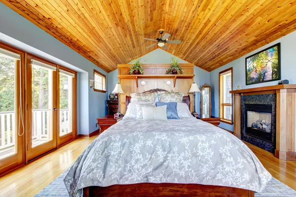 Blauwe slaapkamer met houten plafond en open haard interieur. — Stockfoto