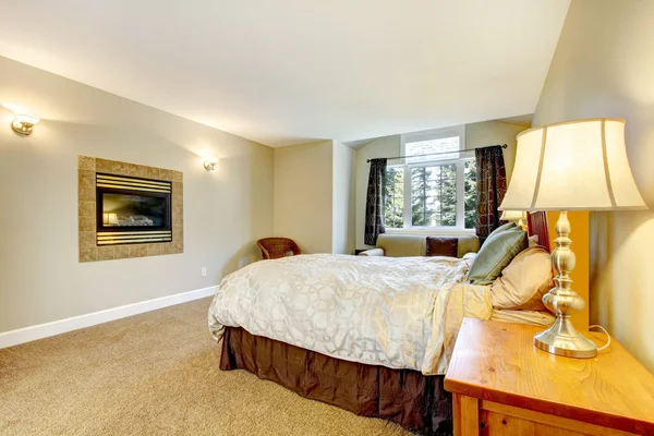 Grote slaapkamer met open haard en nachtkastje met lamp. — Stockfoto