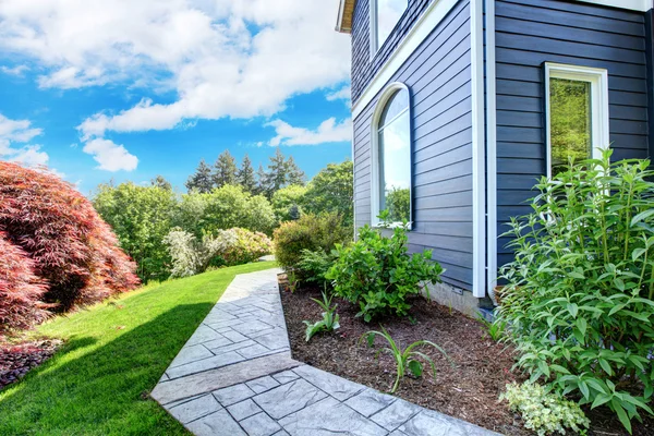 Blauwwitte Huis kant met loopbrug en groene landschap. — Stockfoto