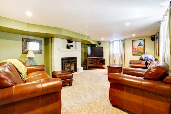 ТВ-зал с зелеными стенами, кожаными диванами и камином . — стоковое фото