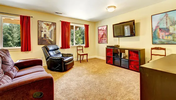 Sala de estar TV com arte e cortinas vermelhas e tapete bege . — Fotografia de Stock