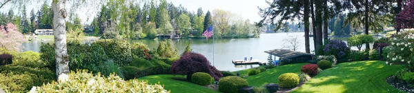 Bakgård landskap med blommande vårblommor och sjön. — Stockfoto