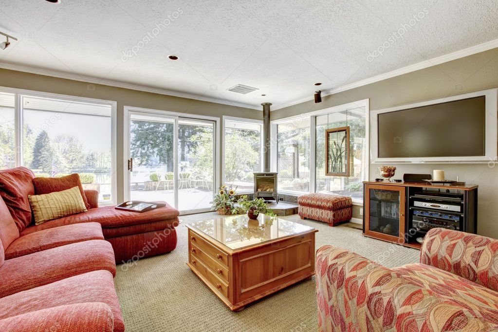 Wohnzimmer mit rotes sofa, beige wände und viele fenster ...