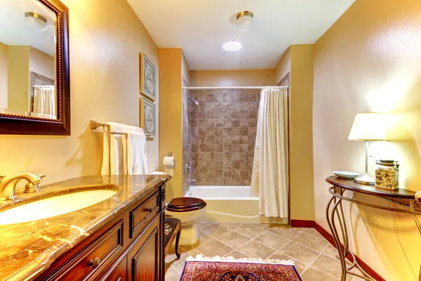 Ouro agradável banheiro com telhas marrons e armário de madeira . — Fotografia de Stock
