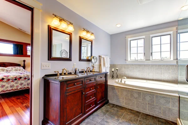 Ładne lavendar łazienka z wanną i drewna szafy z dwie umywalki. — Zdjęcie stockowe