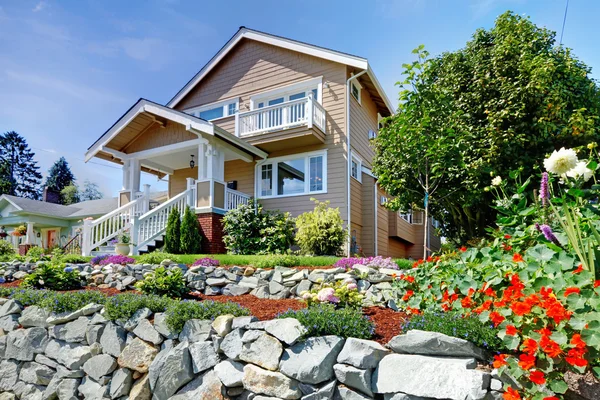 Zweistöckiges beiges schönes Haus auf dem felsigen Hügel mit Blumen. — Stockfoto