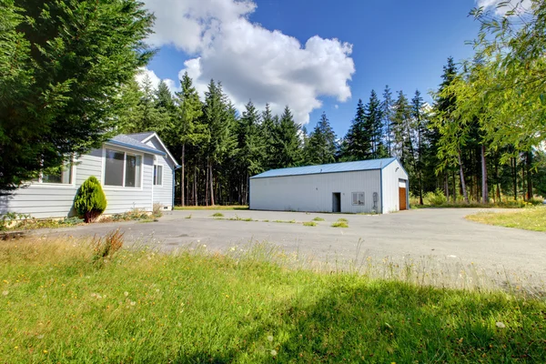 Kleines graues Haus mit Werkstatt und großem Parkplatz. — Stockfoto