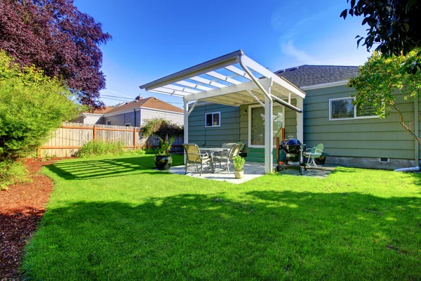 Casa pequeña verde con porche y patio trasero . —  Fotos de Stock