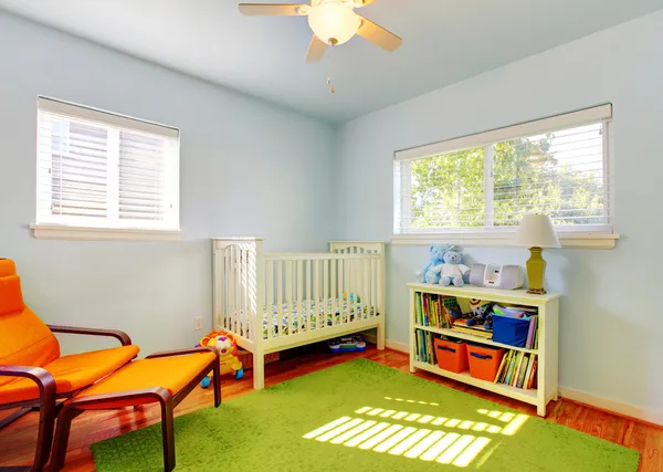 Dziecko przedszkola wystrój zielony dywan, ściany niebieskie i pomarańczowe krzesło. — Zdjęcie stockowe