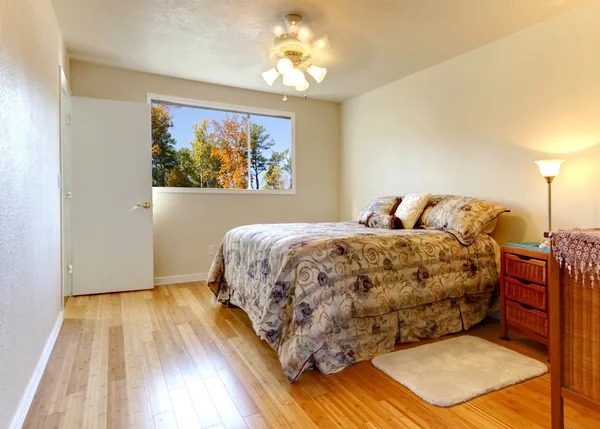 Простая спальня с деревянным полом и осенним видом из окна . — стоковое фото