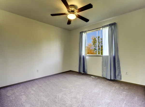 Prázdná místnost s závěsy, šedý koberec a ventilátor. — Stock fotografie
