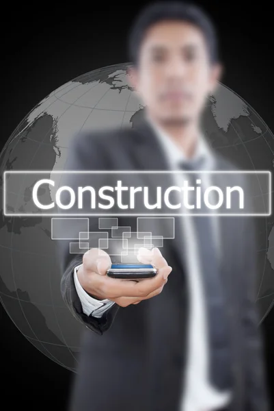 Empresario sosteniendo la palabra Construcción desde el teléfono móvil . — Foto de Stock