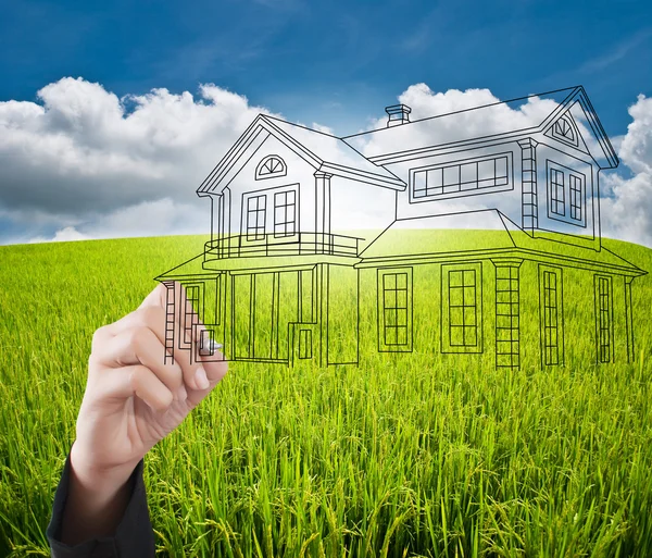 Hand pushing house plan on the blue sky field — Stock Photo, Image