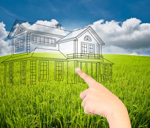 Hand pushing house plan on the blue sky field — Stock Photo, Image