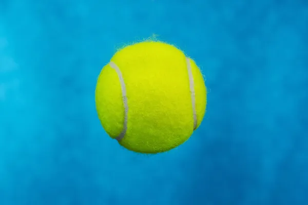 Bola de tênis no céu fundo azul — Fotografia de Stock