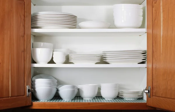 Nuevos platos blancos y cuencos en el gabinete de cocina — Foto de Stock