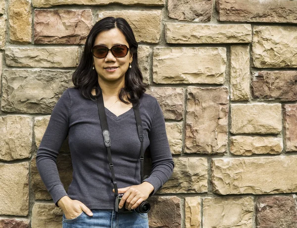Asiatische Frauen halten Kamera gegen Steinmauer — Stockfoto