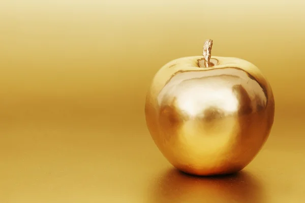 Золотое яблоко на золотом фоне — стоковое фото