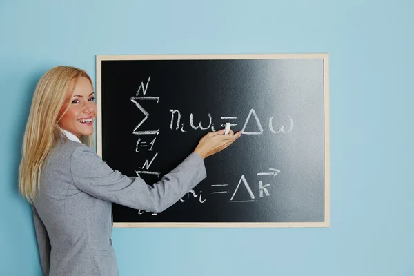 Young woman teacher in front of a blackboard — Stock Photo, Image