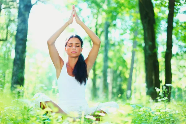 Mladá žena dělá jógu cvičení v zeleném parku — Stock fotografie