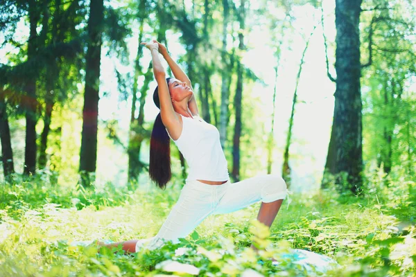 Молода жінка займається вправами йоги в зеленому парку — стокове фото