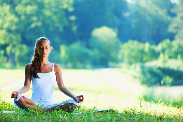 Mujer joven haciendo ejercicio de yoga en el parque verde —  Fotos de Stock