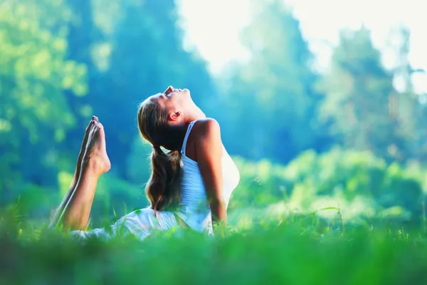 Giovane donna che fa esercizio di yoga nel parco verde — Foto Stock