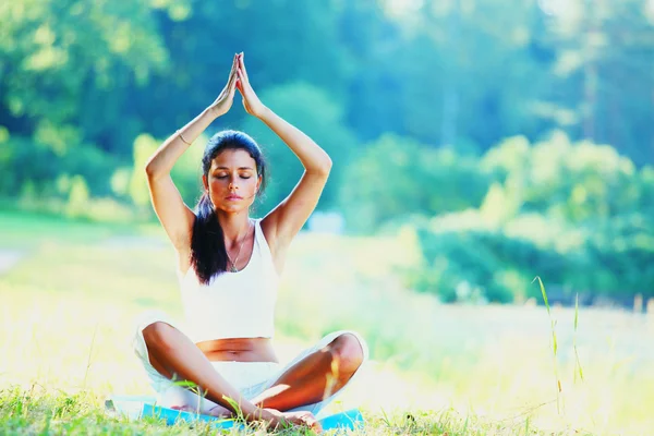 Jonge vrouw doet yoga oefening in groen park — Stockfoto