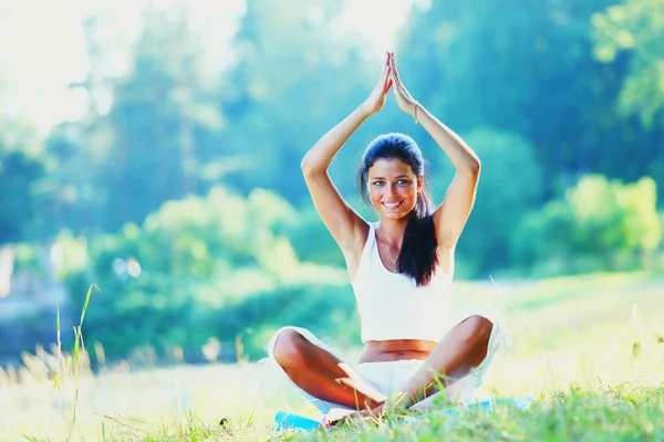 Junge Frau macht Yoga-Übungen im grünen Park — Stockfoto