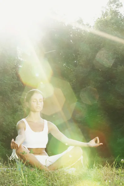 Ung kvinna som motionerar yoga i grön park — Stockfoto