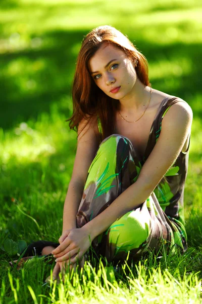 Brunetka siedzi na zielonej trawie — Zdjęcie stockowe
